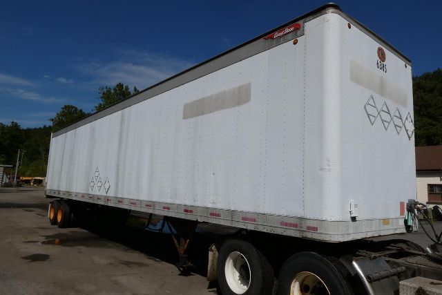 Great Dane trailer with white exterior and dual axles, side view showing diamond placards and rear hitch.