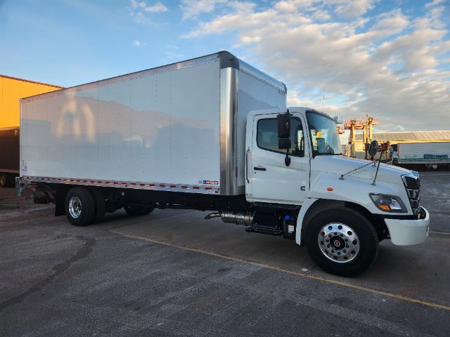 Box truck side view with white cab and large rectangular cargo box, Hino branding on front grille, chrome fuel tank, and dual rear wheels.