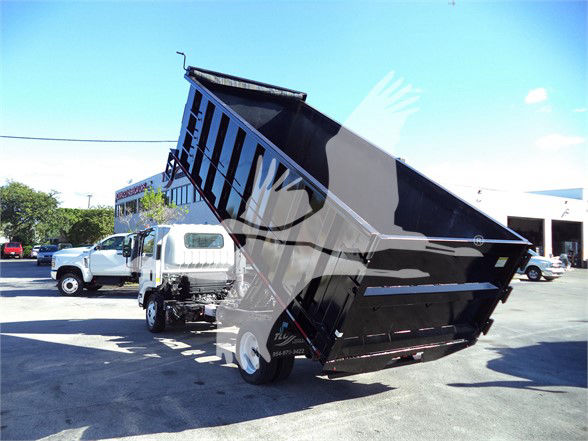 Isuzu 2017 NRR dump truck with bed raised, showing dump hopper and chassis in a used trucks lot.