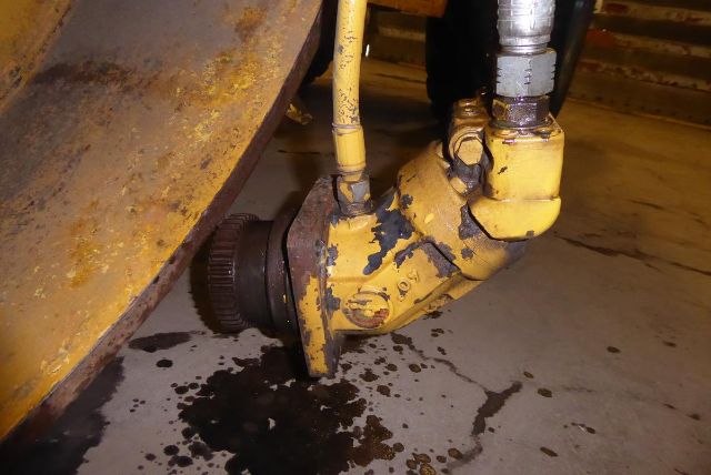 Tractor studded joint and hydraulic hose on Bomag BW212D-2 front wheel assembly showing yellow paint and wear.