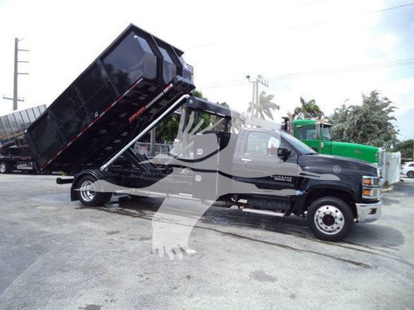 A black Chevrolet Silverado 6500HD truck with a raised dump bed in a dealership lot.