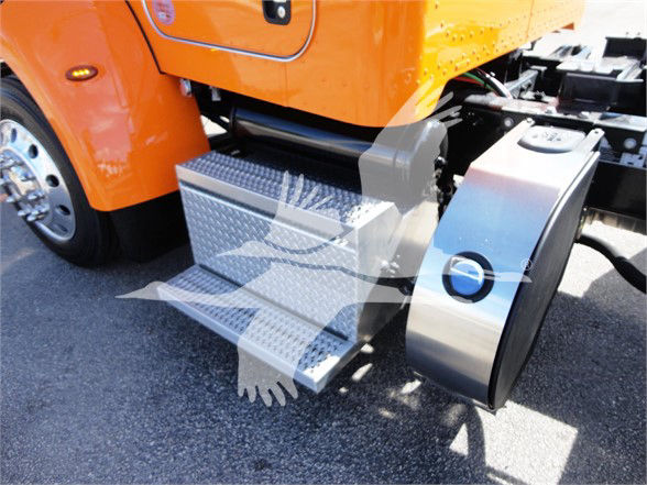 Peterbilt 337 side steps and fuel tank area visible on orange truck cab with diamond plate steps and chrome fuel tank cover.