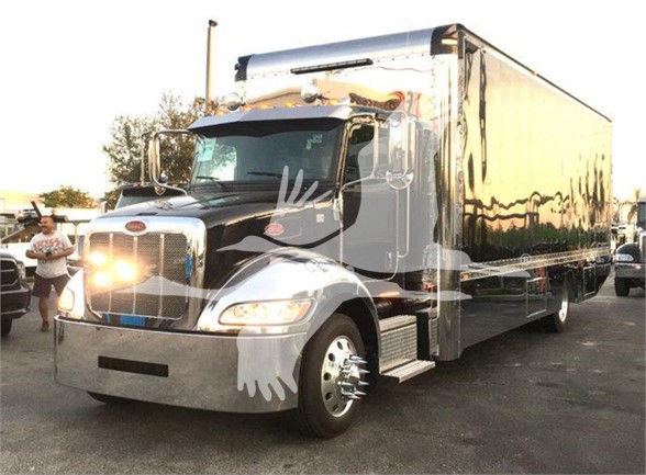 Peterbilt 337 box truck in a parking lot, black cab with chrome bumper and large cargo box, front headlights on, stock number J56602.