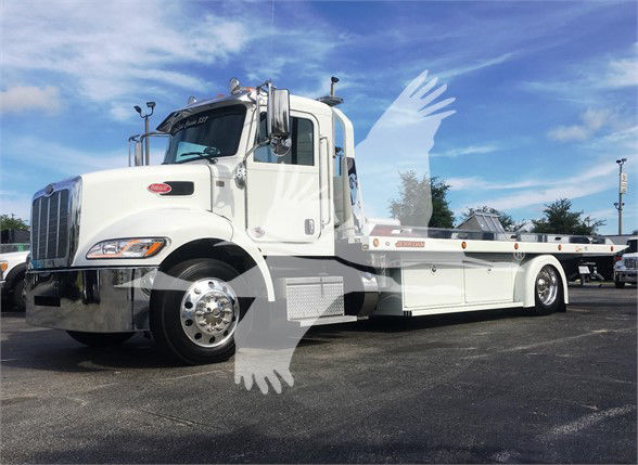 Peterbilt 337 tow truck chassis, white, long flatbed with chrome bumper and wheels, side mirrors, blue sky.