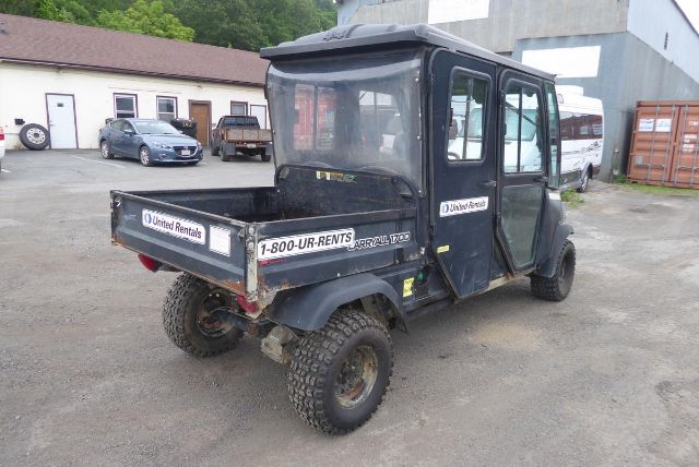 Club Car Carryall 1700 utility vehicle in a used condition with a cargo bed, enclosed cabin, off-road tires, and stickers reading 1-800-UR-RENTS on the bed sides.
