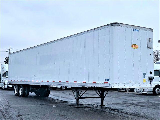 2013 Stoughton dry van trailer in side view showing elevated landing gear and tandem axles with white riveted panels.