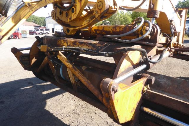 Caterpillar 16G grader attachment with hydraulic hoses and yellow mounting frame.