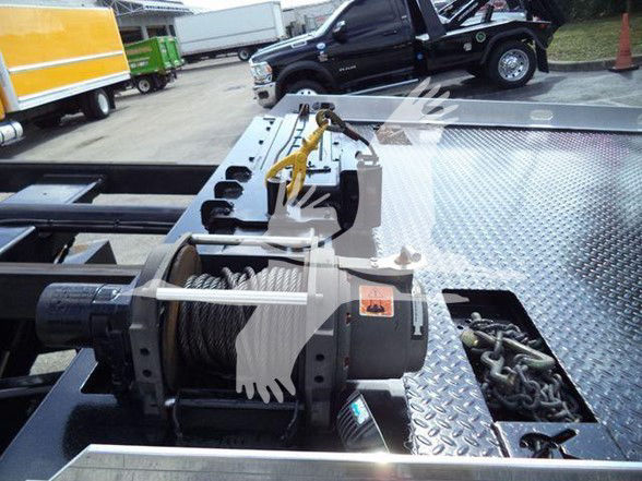 Tow truck bed with hydraulic winch and coil cable, on diamond plate deck, Hino 258ALP truck in background.