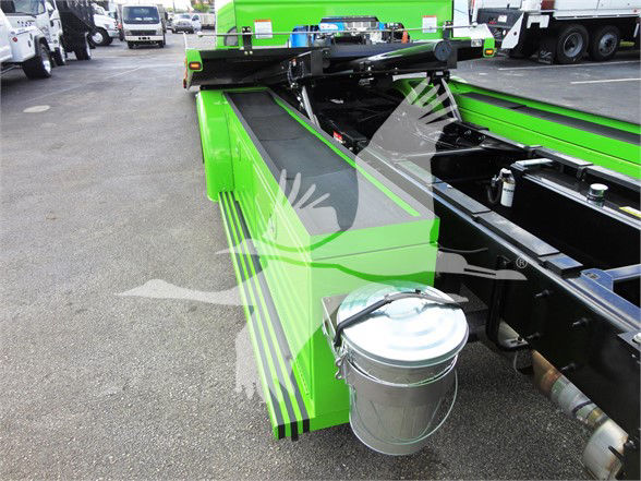 Peterbilt 337 tow truck chassis with bright green accents and a mounted metal bucket on the side, showing the truck frame and hydraulic components.
