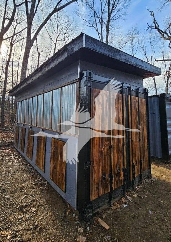Container trailer side view with wood paneling and metal frame, with a triangular roof overhang; watermark of a flying bird across the center.