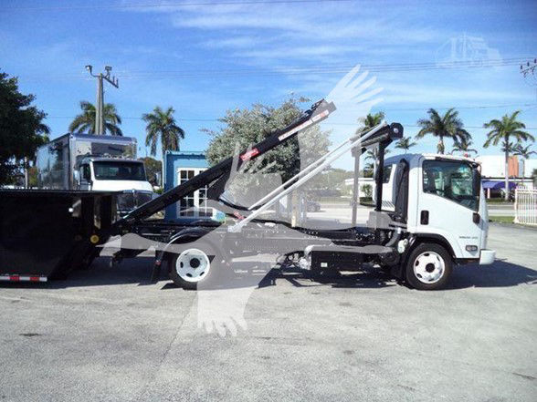 Isuzu NRR wrecker truck side view showing crane hoist and compactor equipment with white cab and black crane arms.