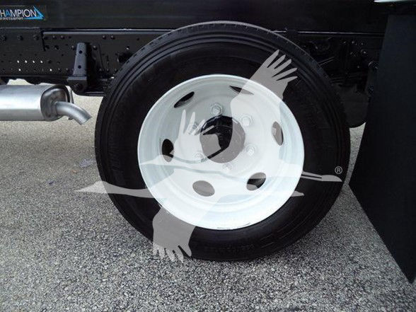 Chevrolet W4500 truck wheel area showing white steel rim and black tire, part of a dump truck chassis with exhaust pipe visible.