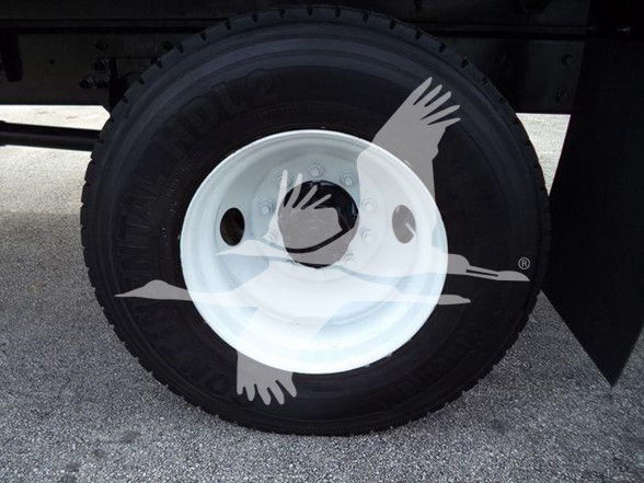 Truck wheel with white rim and tire; faint overlay of hands and a bird graphic. No specific labels or text visible on the wheel or surrounding area.