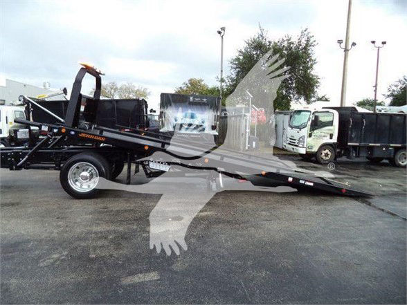 2024 Ford F750 SD tow truck chassis with a low-profile flatbed and equipment visible in the background.