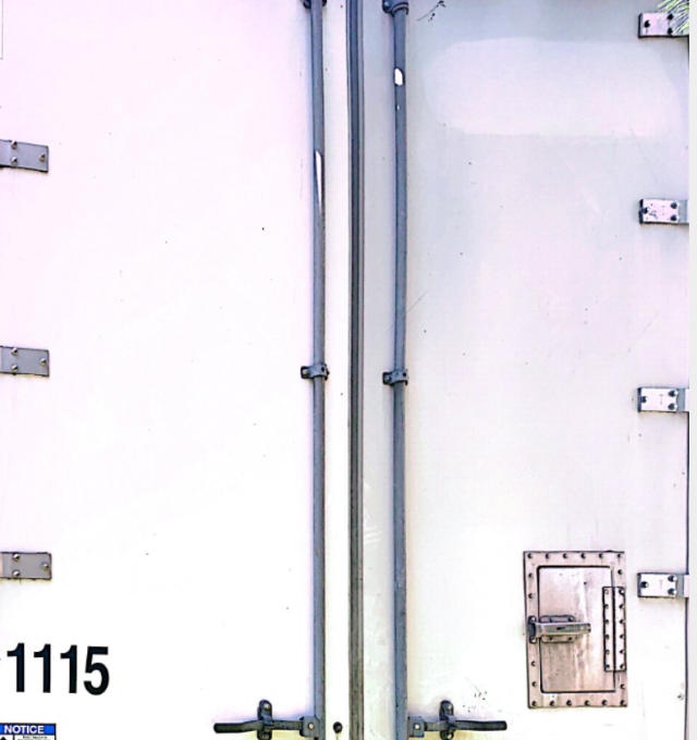 Trailer rear doors with vertical seams and a small access hatch on the right door. Stock number 1115 partially visible at bottom left.
