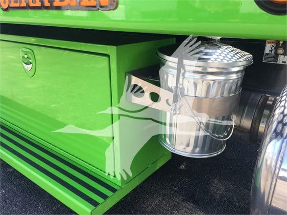 Green Peterbilt truck with metal chrome exhaust canister and integrated toolbox, side view showing steps and wheel area.