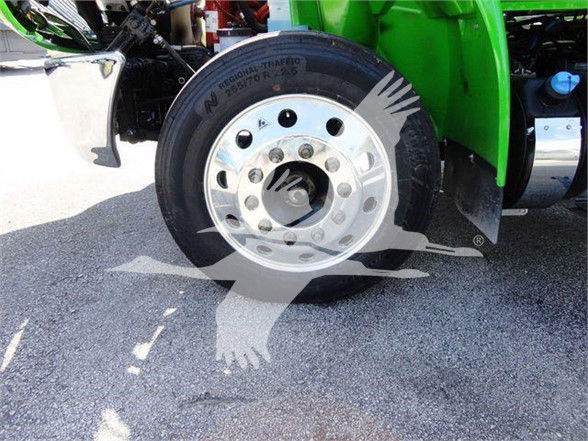 Truck wheel and tire on the front of a green 2023 International MV chassis showing a polished steel rim with lug nuts.