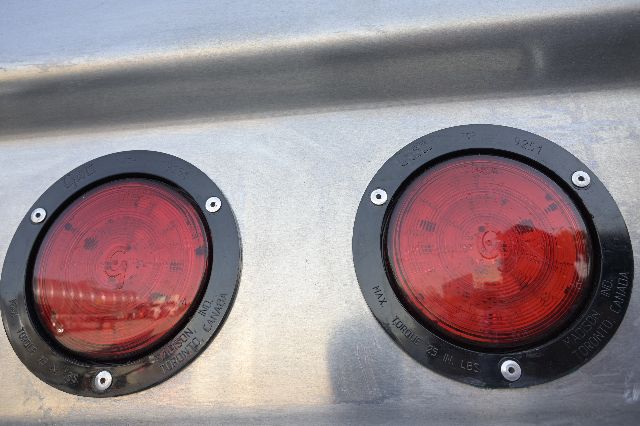 Two red circular tail lights on a silver aluminum trailer side.