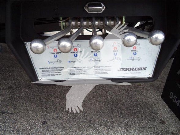 Control panel with levers for tow options, winch, and roll functions on a Jerr-Dan system mounted under a truck.