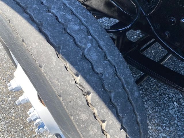 Truck wheel and dual tires showing tread pattern and wheel studs, undercarriage components visible.