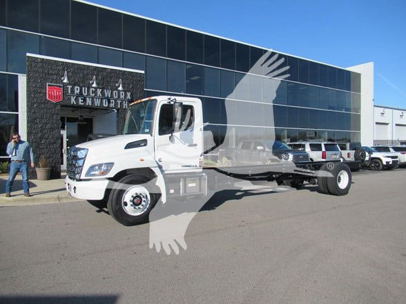 Truck shown in front of a dealership building, white cab, flatbed chassis with no cargo, VIN and stock info not visible on image.