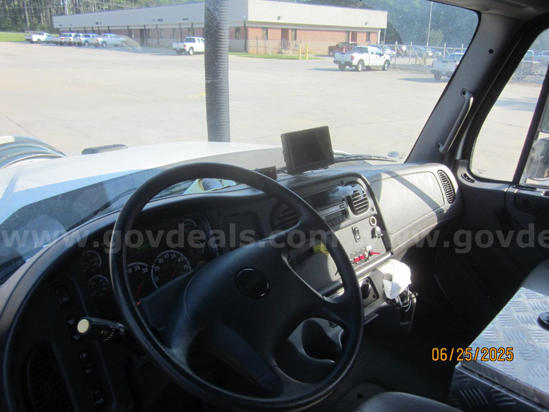 Truck cab interior showing steering wheel dashboard and GPS mount with gear selector and control panel.