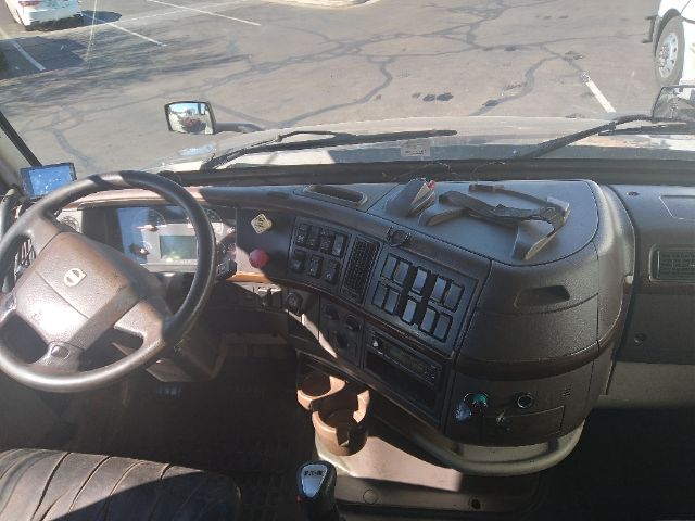 Truck interior dash of a Volvo with steering wheel showing instrument cluster, center console with multiple switches, and gear shifter in view.