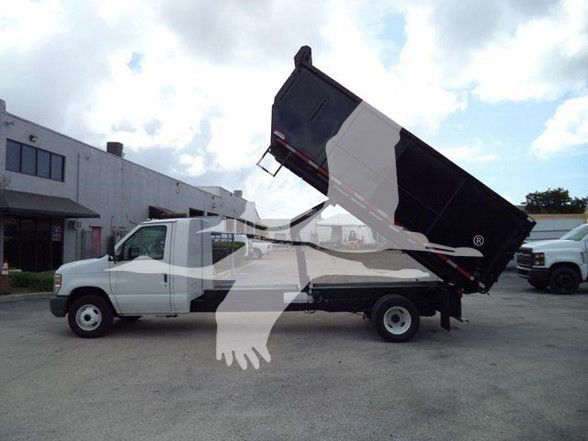 Ford E-450 dump truck side view showing white cab and black dump bed raised.