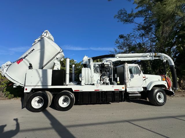 Side view of a white vacuum truck with a large rear cement mixer/vacuum tank and crane, showing 'MACON' on the tank