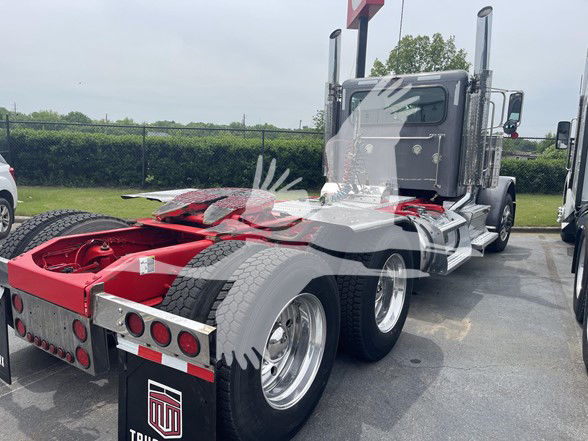 Peterbilt 389 tractor rear/side view showing chassis and cab, aluminum wheels, dual rear axles, red frame components, reflection on window.