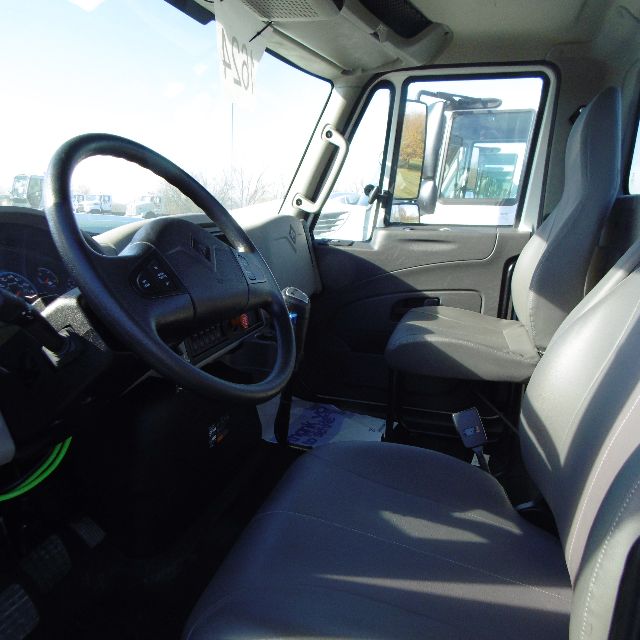 Cab interior of a 2016 International 7400 SBA truck showing steering wheel, driver seat, and passenger seat with dashboard details.