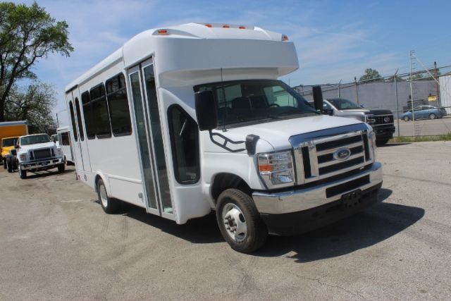 Ford E450 shuttle bus in white, front three-quarter view with extended passenger doors open, bus body and chrome front grille visible.