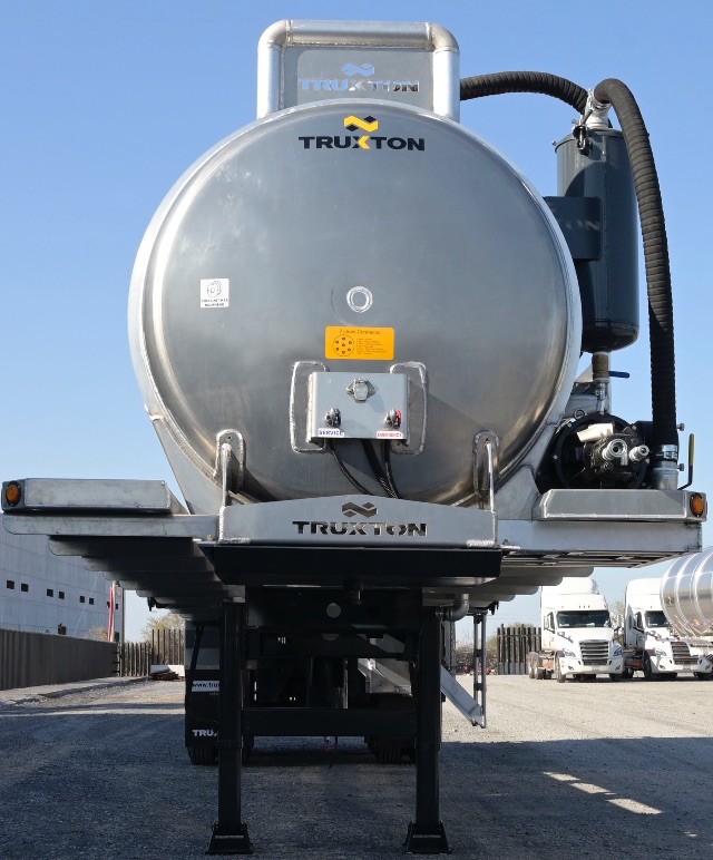 Truxon aluminum vacuum trailer rear view with circular tank, black support legs, and hoses; branding 'TRUXTON' on tank and frame.