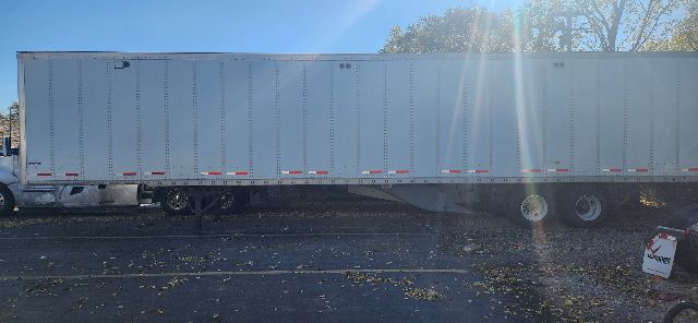 Flatbed trailer side of a 2014 Wabash dry van with riveted aluminum side, wheels and undercarriage visible.