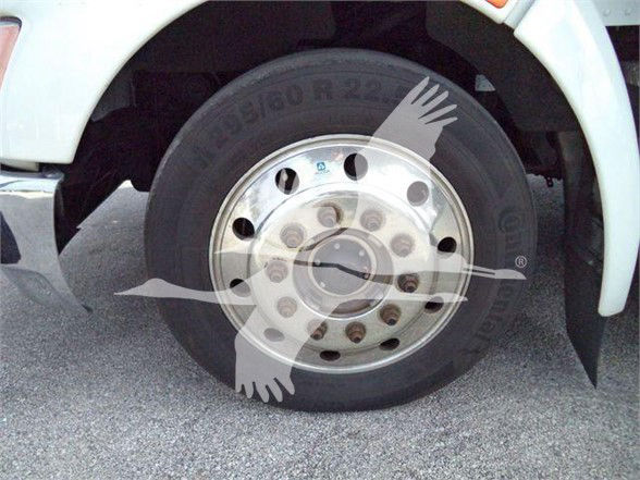 Kenworth T370 wheel and tire close-up showing front hub and lug nuts, with white fender and partial wheel well.