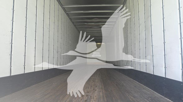 Trailer interior showing empty cargo space with metal walls and wooden floor.