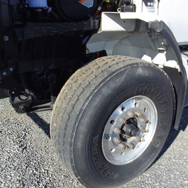 Truck front wheel and fender of a 2016 International 7400 SBA 6X4 showing Goodyear tire and wheel with rusted lug nuts.