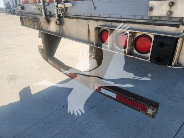 Rear view of a Utility 3000R trailer showing bumper, red taillights, and reflective safety strip with visible wear.