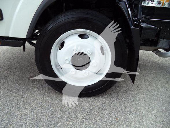 Wheel close-up of a white dump truck with a black tire and white rim, partial undercarriage visible.