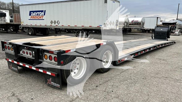 Double drop expandable trailer with wood deck and two axles, Dayon Freight signage on white trailer in background. Visible rear and side ramps, reflective strips, wheels, and mud flaps.