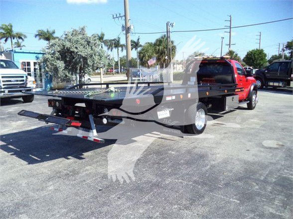 Tow truck flatbed with Ram 5500 in foreground, rear view shows tow setup and chassis; no legible odometer or fluid labels visible.
