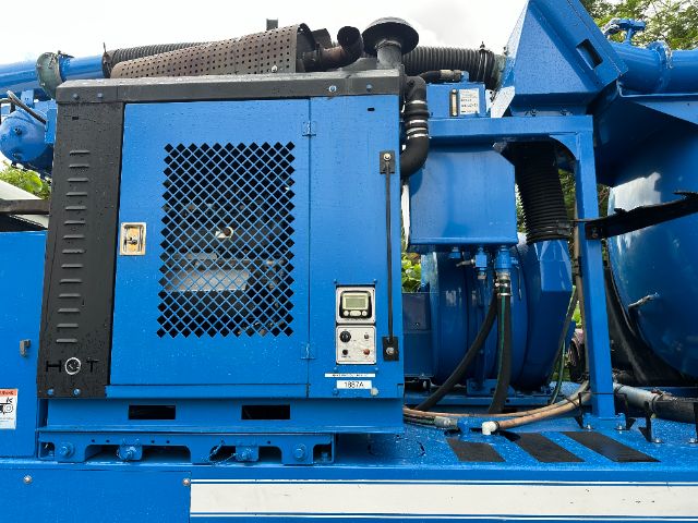 Mack GU713 vacuum truck equipment showing blue engine housing with ventilation grate and control panel.