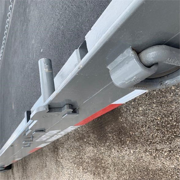 Container trailer side showing locking mechanism and caster wheel with grey paint.