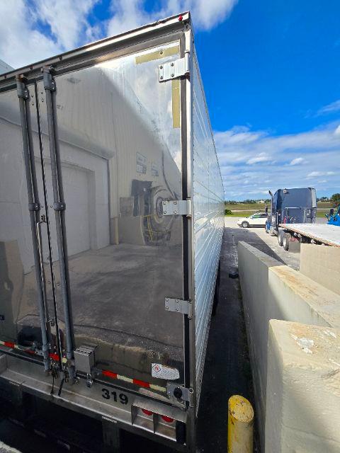 Great Dane trailer rear door open with reflective aluminum panel, hinges, and bungee straps; catalog shows '319' on lower bumper.