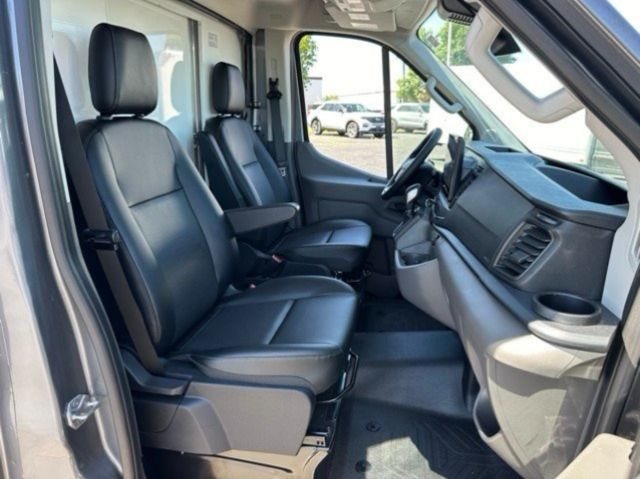 Ford Transit 350 box truck interior with front captain seats and steering wheel, black leather-like seats, dashboard, driver and passenger seats visible.