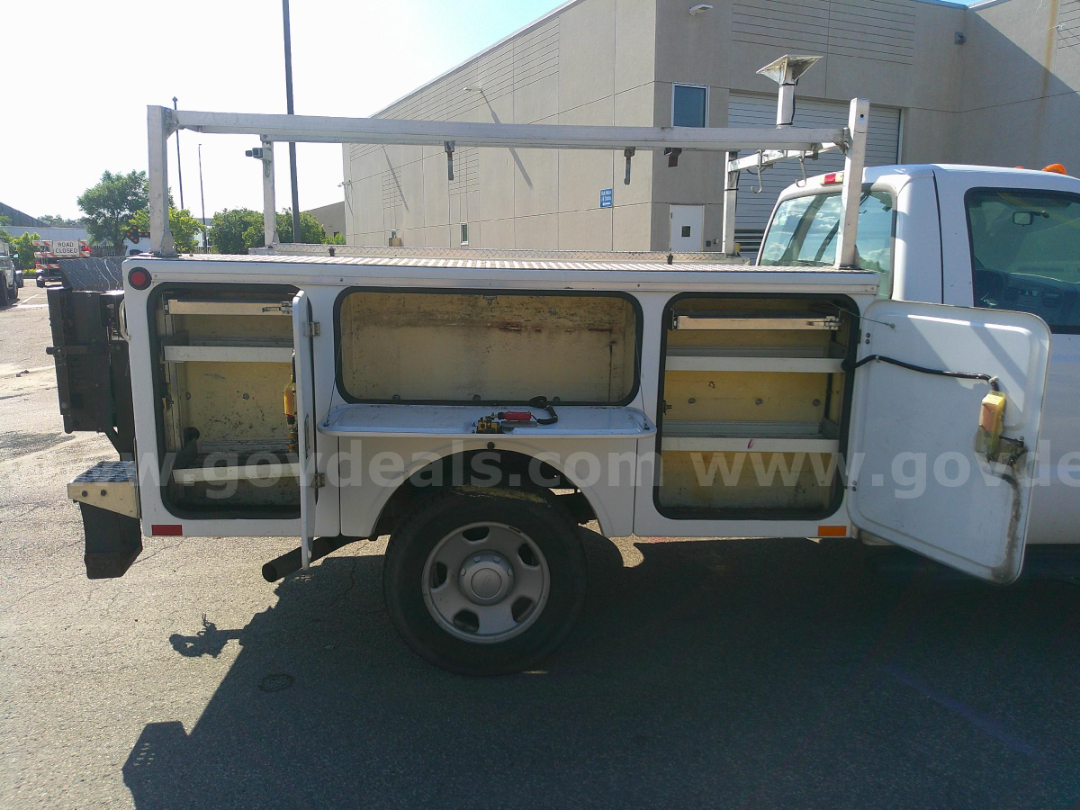 Service/Utility truck side compartments open showing storage shelves and metal ladder rack on top.