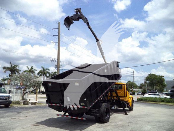 Dump truck with a grapple attachment and a large dumped load, crane arm extended over the bed.