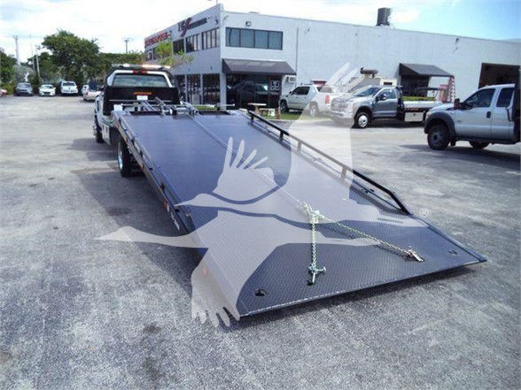 Endless flatbed tow truck trailer showing a black steel ramp at the rear with latches and chains.