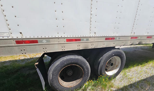 Trailer dual rear wheels of a utility trailer with riveted aluminum sides and reflective strips