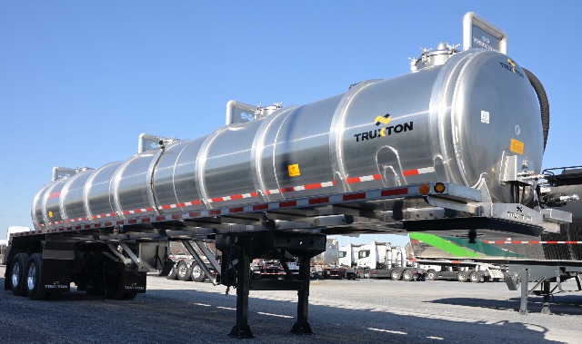 Truxton aluminum vacuum trailer tank on tandem axle with ladder and reflective tape, TRUXTON logo visible on tank.